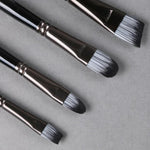 Set of black paintbrushes with silver ferrules on a gray background
