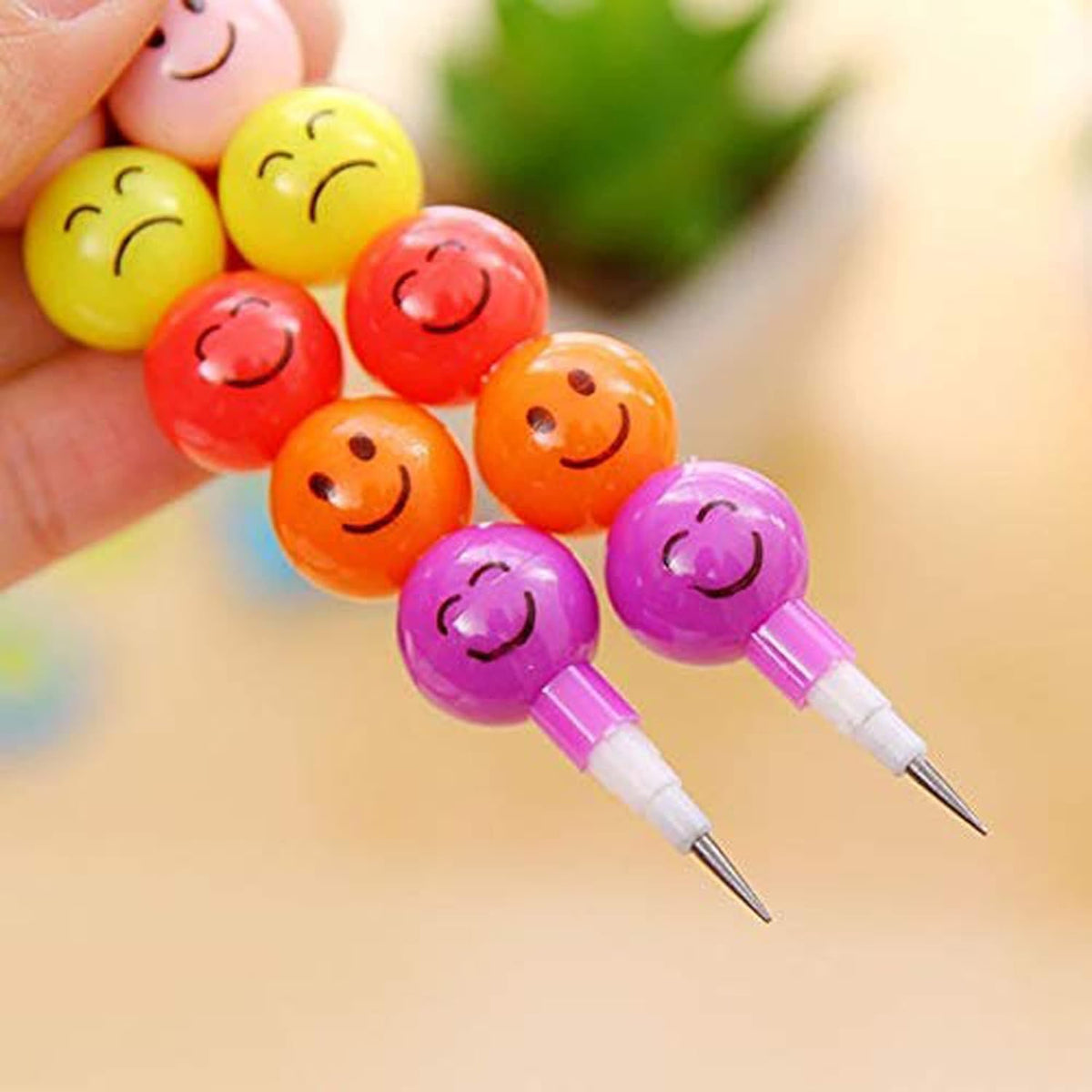Colorful smiley face pens held by a hand with a blurred background