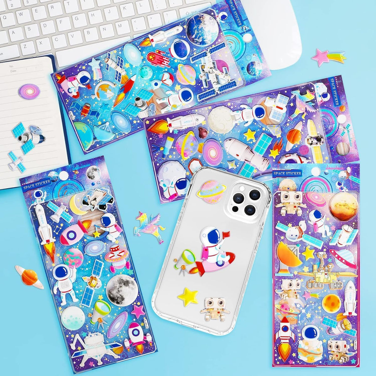 Colorful space-themed stickers on a blue surface with a phone displaying one of the stickers.