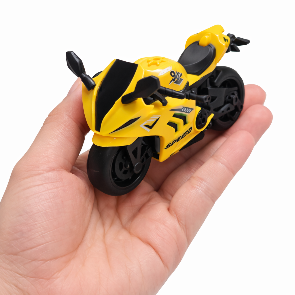 Yellow toy motorcycle held in a hand against a white background