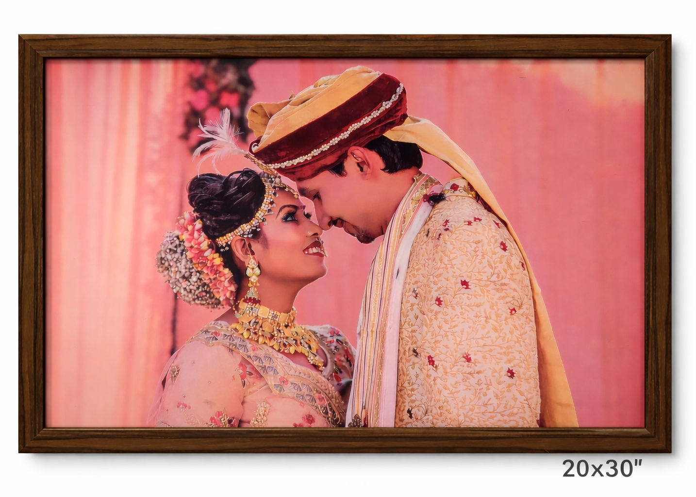 Framed photograph of a couple in traditional wedding attire against a pink background