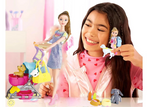 Young girl playing with dolls and toys in a room with pink walls.