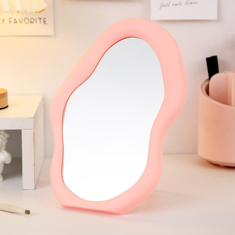 Pink makeup mirror on a surface with a blurred background