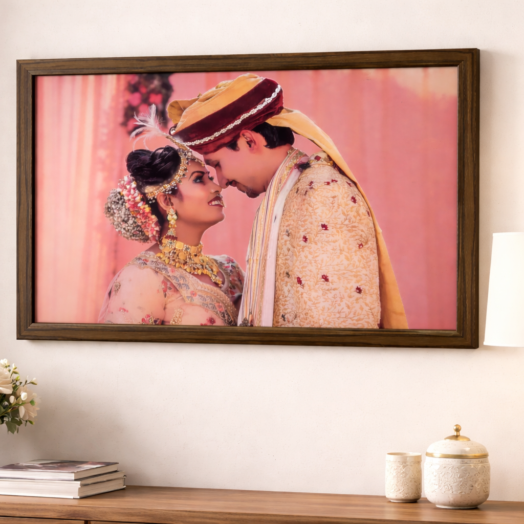 Framed artwork of a couple embracing on a pink background, displayed on a wall above a wooden console table.