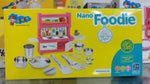 Box of SNNY Nano Foodie kitchenware set with various utensils and cookware on a yellow background.