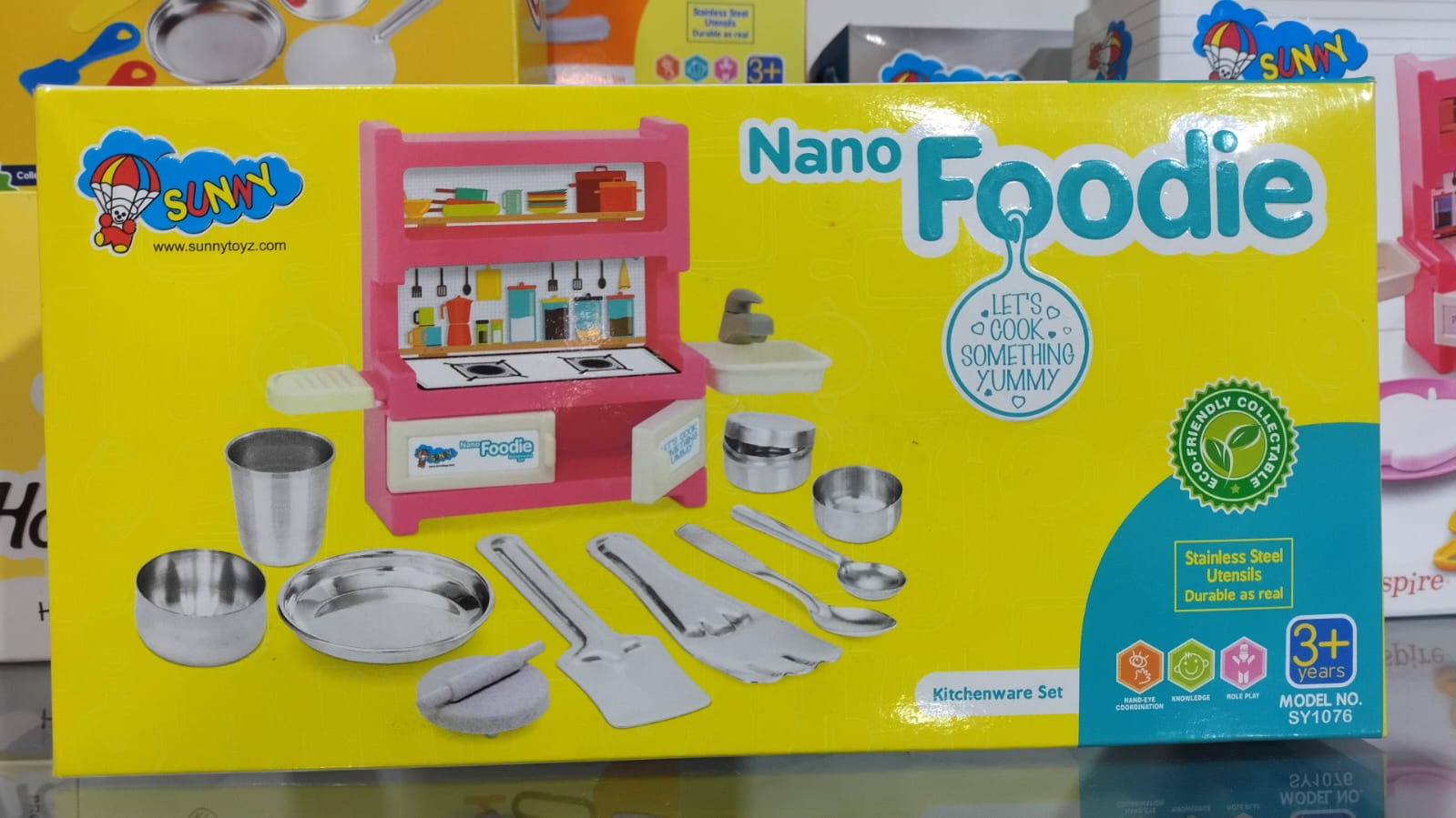 Box of SNNY Nano Foodie kitchenware set with various utensils and cookware on a yellow background.