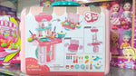 Toy kitchen set with dolls and accessories in the background