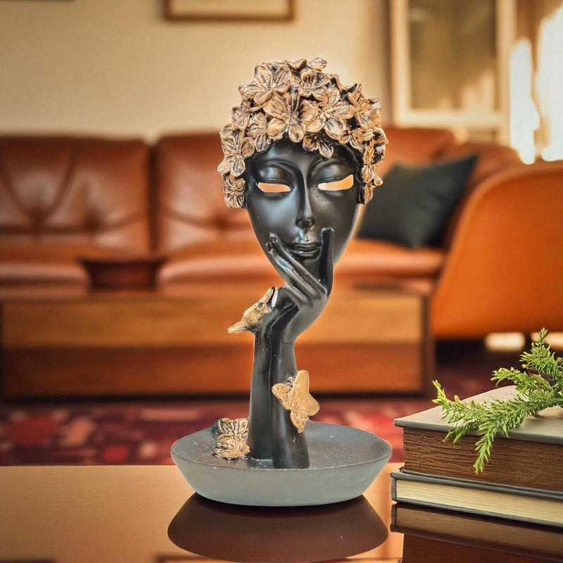 Decorative sculpture of a face with floral crown on a table in a living room setting