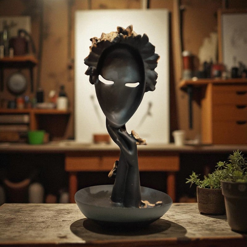 Decorative sculpture of a faceless figure with a bowl on a table in a workshop setting