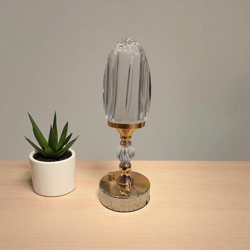 Decorative glass object on a wooden surface with a small potted plant.