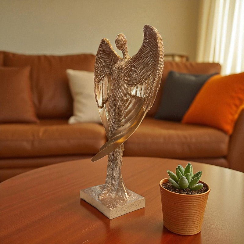 Decorative angel sculpture on a table with a potted plant, in front of a brown sofa.