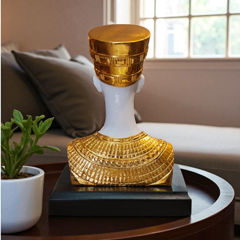 Decorative object with gold and white design on a table with a plant and sofa in the background