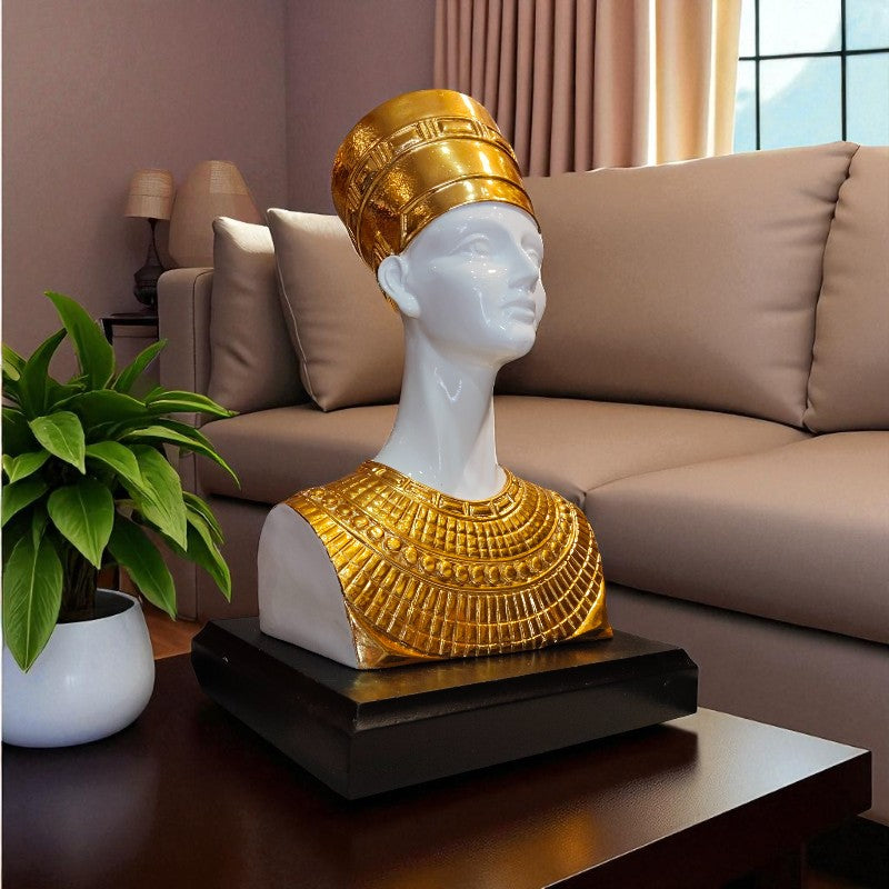 Decorative sculpture of a head with gold headpiece and jewelry on a table in a living room.