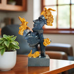 Decorative statue with gold accents on a table next to a plant