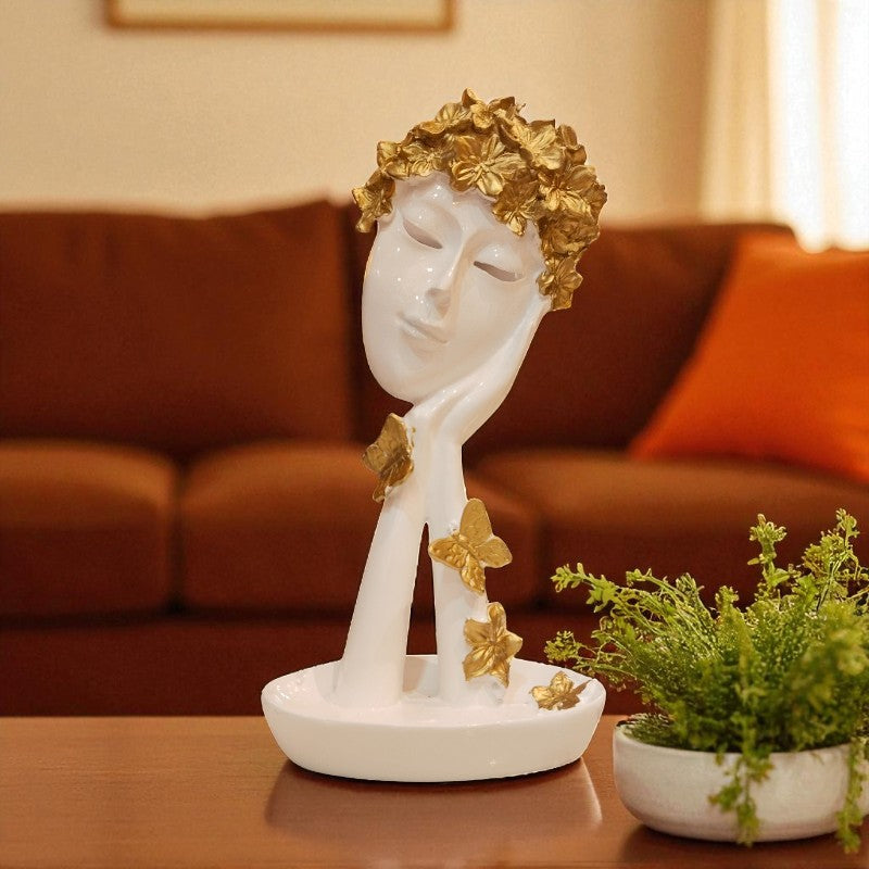 Decorative sculpture of a face with gold accents on a table in a living room setting.