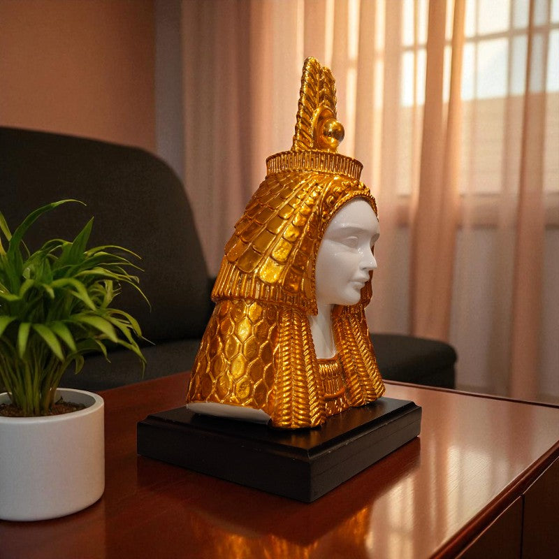 Decorative object with gold headpiece on a table next to a plant