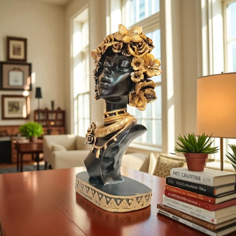 Decorative statue on a table with books and a lamp in a room setting