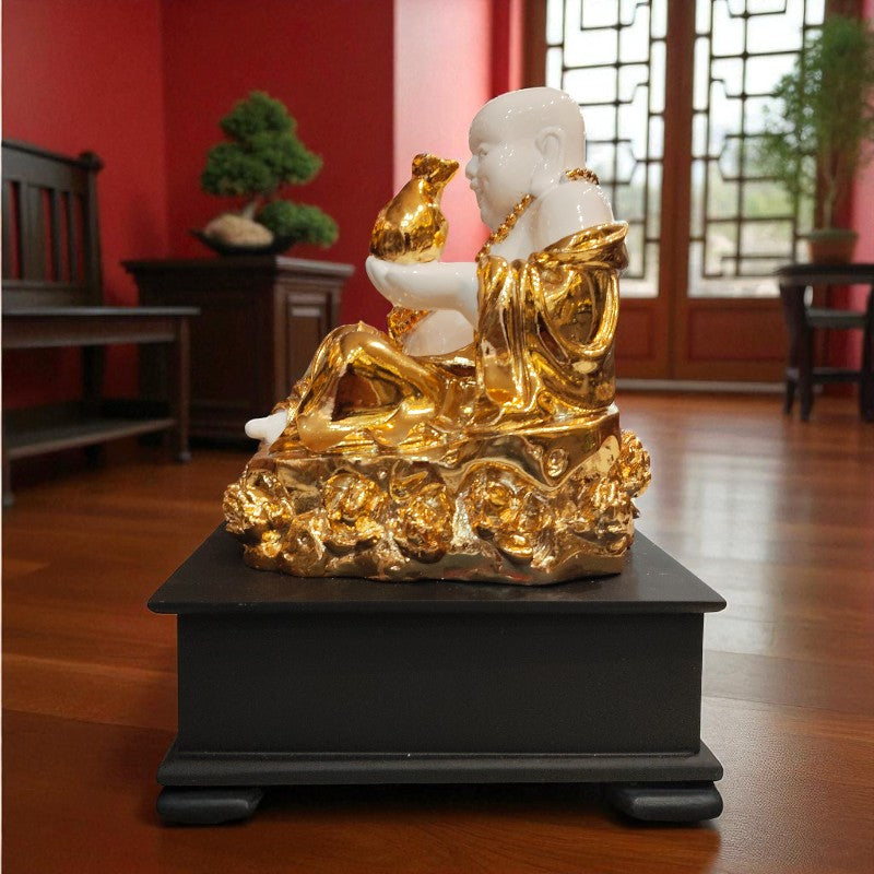 Gold and white statue on a black base in a room with red walls and wooden floor.