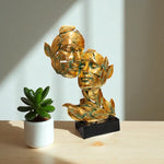 Gold leaf sculpture on a wooden surface with a potted plant