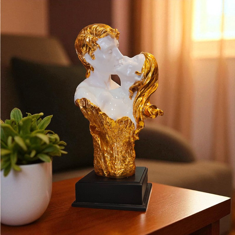 Decorative sculpture of a woman with gold and white finish on a wooden table.