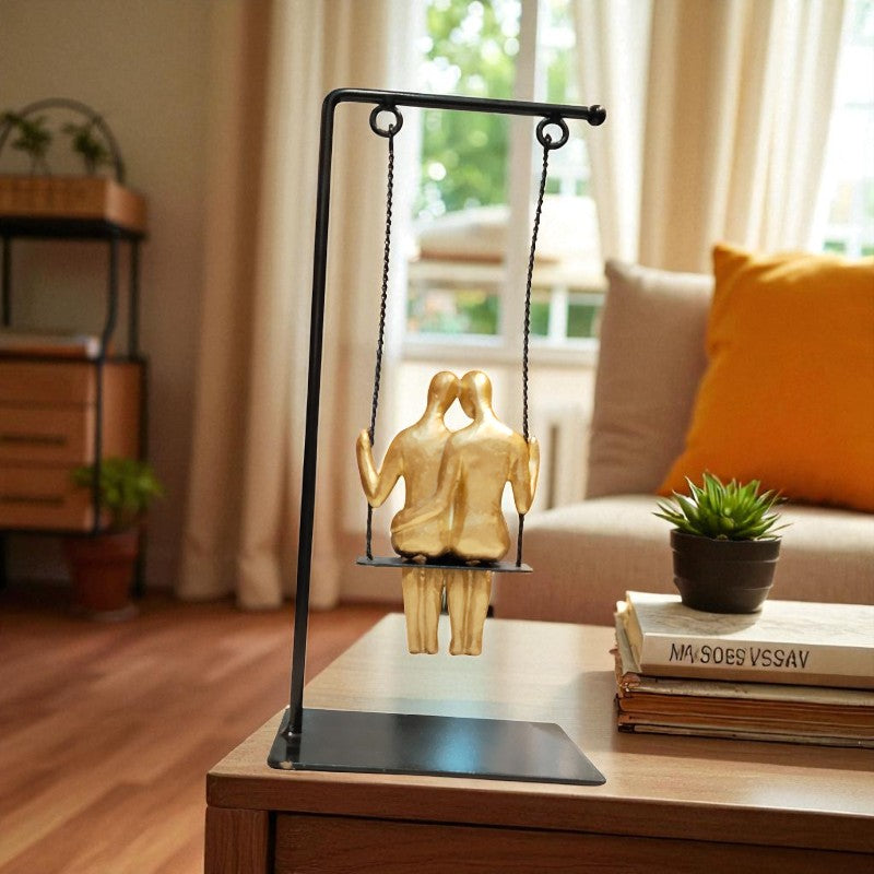 Decorative sculpture of two people on a swing on a table in a living room.