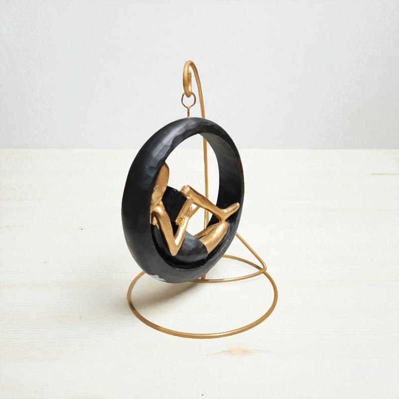 Decorative sculpture of a person in a black chair on a white background