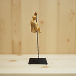 Gold climbing figure on a black stand against a wooden background
