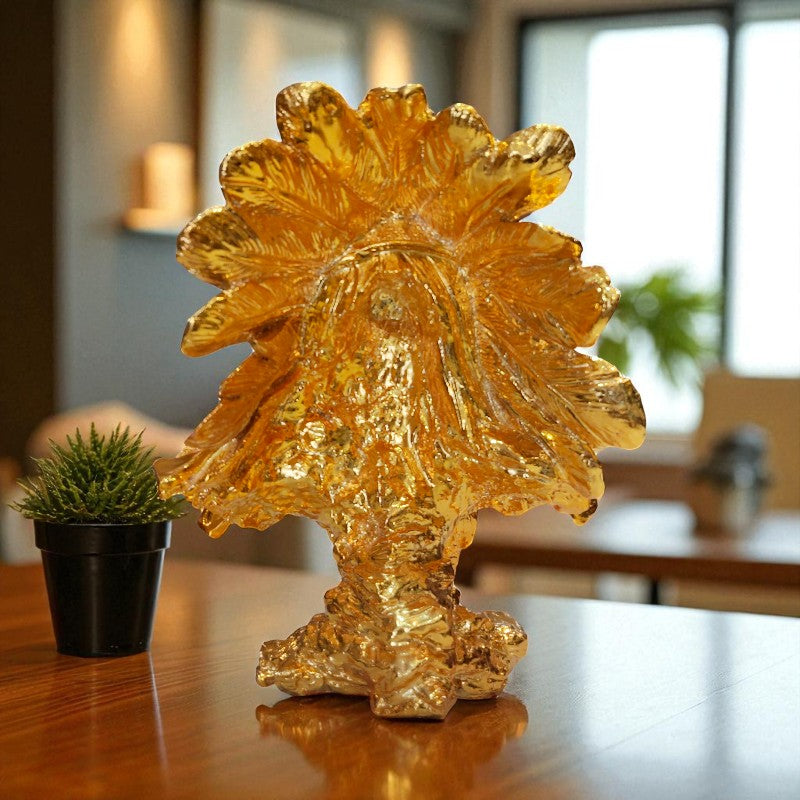 Gold leaf sculpture on a wooden table with a blurred indoor background