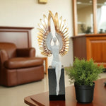 Decorative sculpture of a winged figure on a table with a blurred background