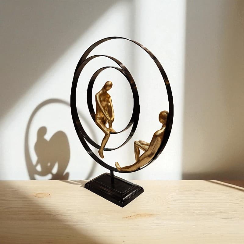 Decorative sculpture of two figures sitting on a circular platform with a soft background