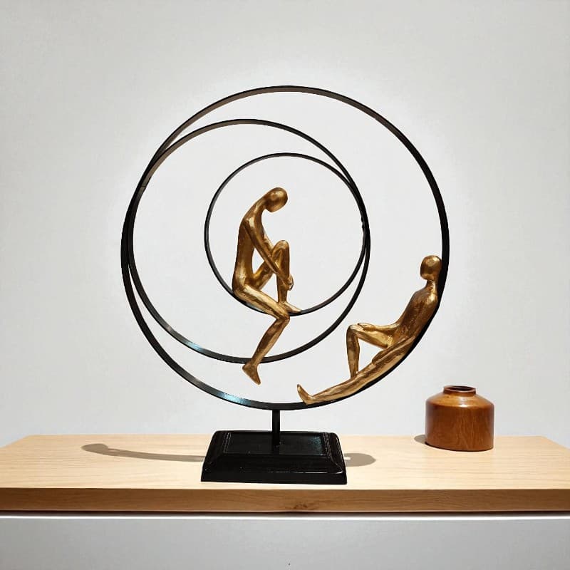 Decorative sculpture of two figures in a circular design on a wooden surface with a plain background