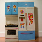 Close up of modern kitchen playset toy with stove, fridge and blue cabinets decorated with cute character stickers.