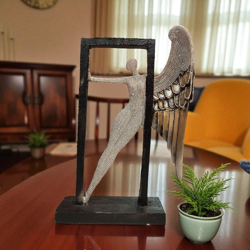 Decorative sculpture of a figure with wings on a stand in a room setting.