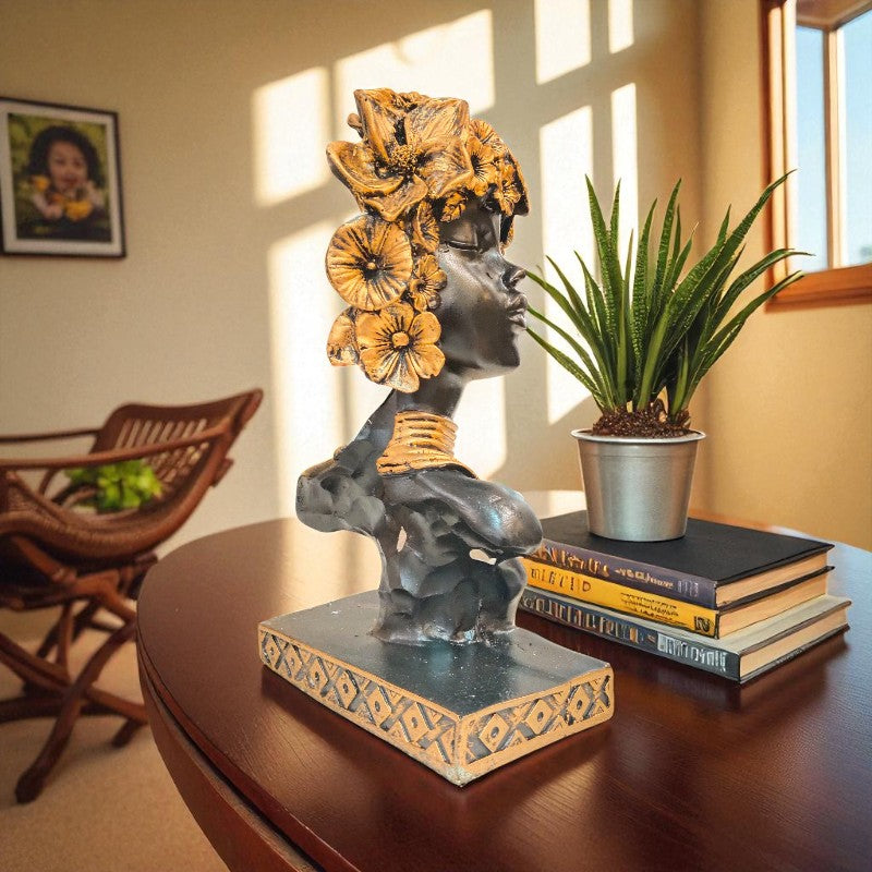 Decorative statue of a woman with flowers on her head on a table with books and a plant.